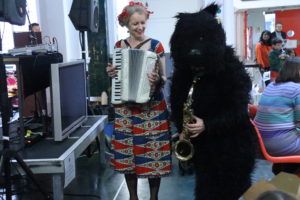 performance: Delpha with accordion next to a man dressed as a bear
