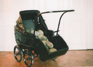old fashioned pram painted black with granite egg stones and text